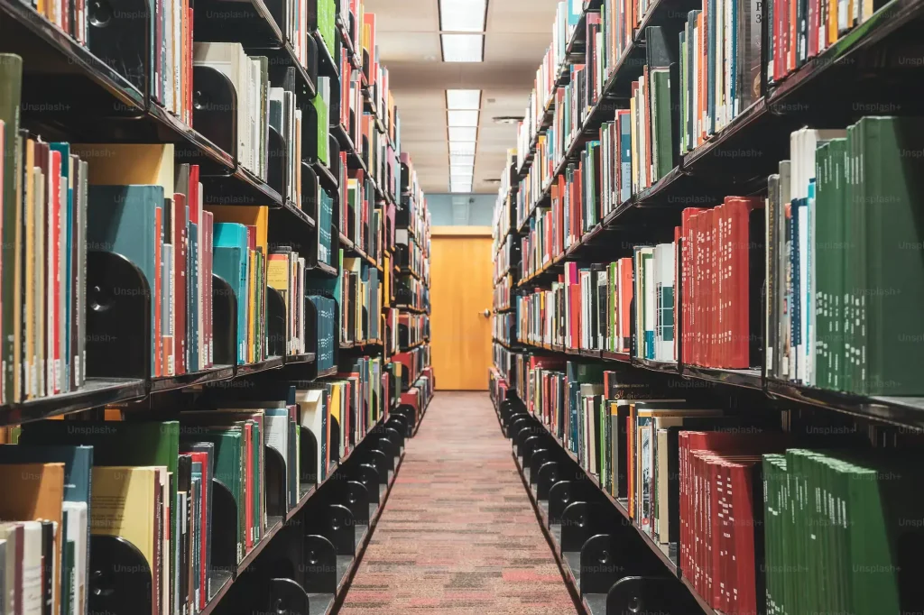 An aisle in a public library, showing filled bookshelves on either side